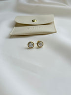 Gold moissanite earrings with a matching pouch on a white background