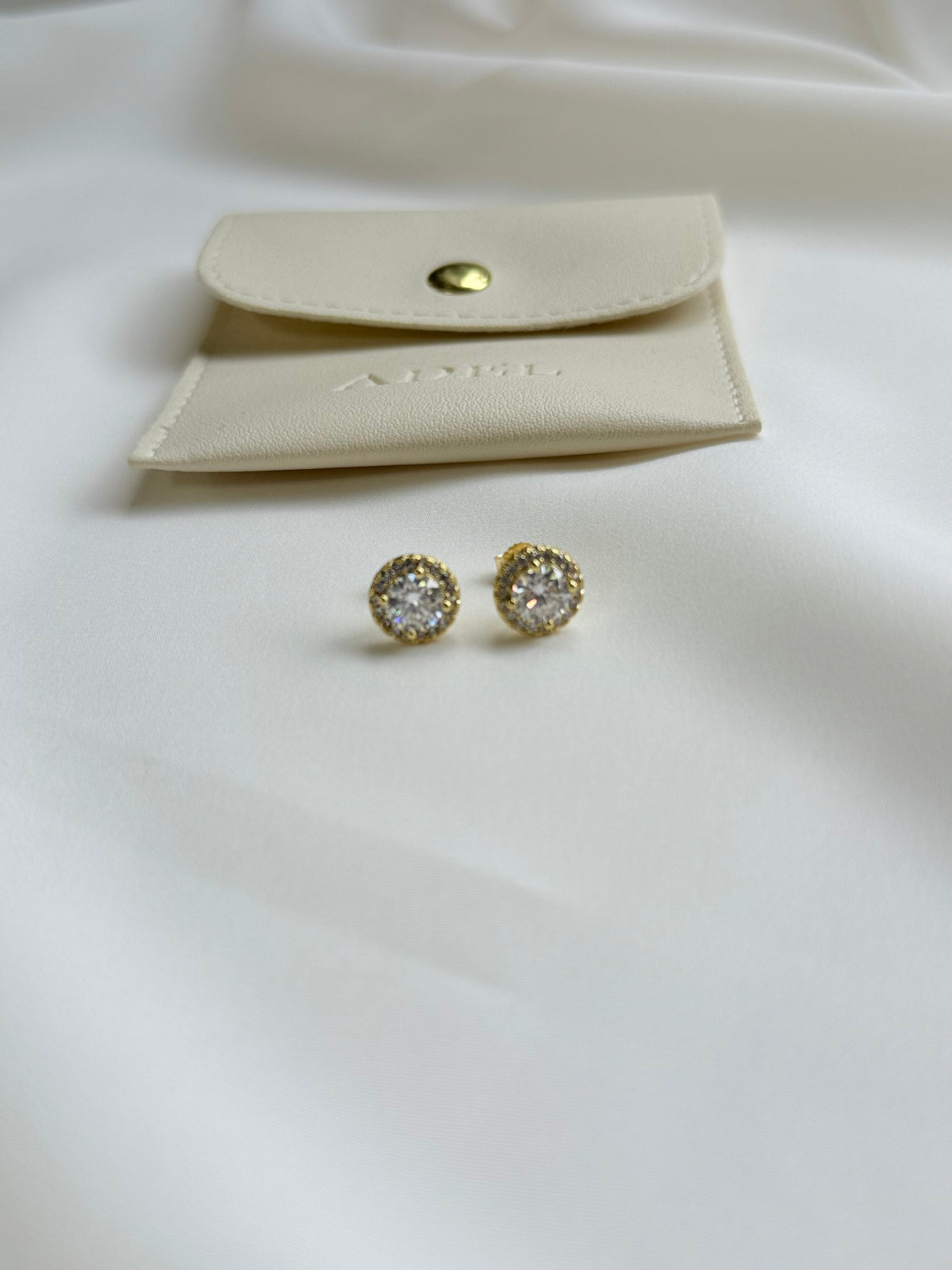 Gold moissanite earrings with a matching pouch on a white background