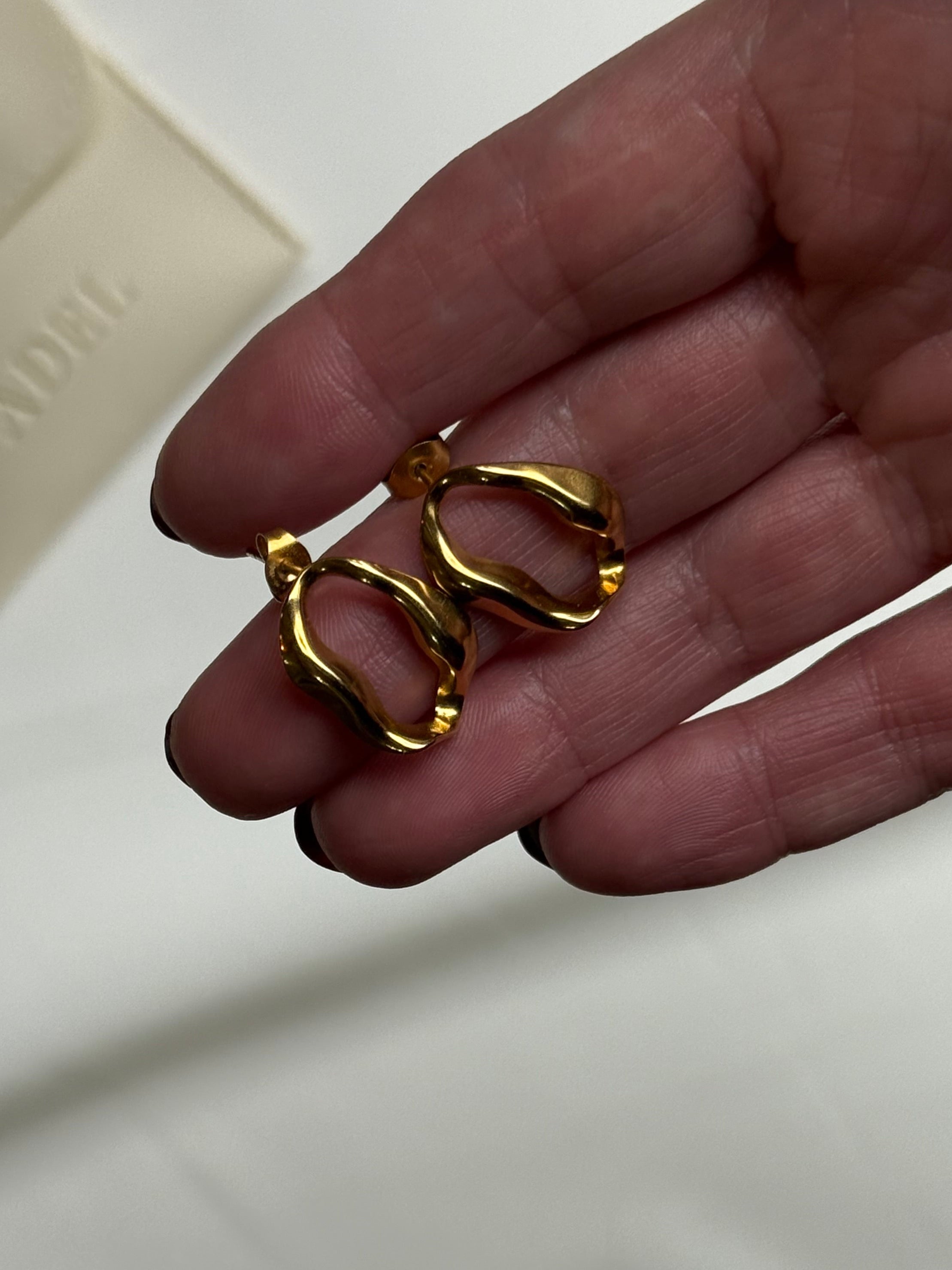 Gold rings held in a hand with a blurred background