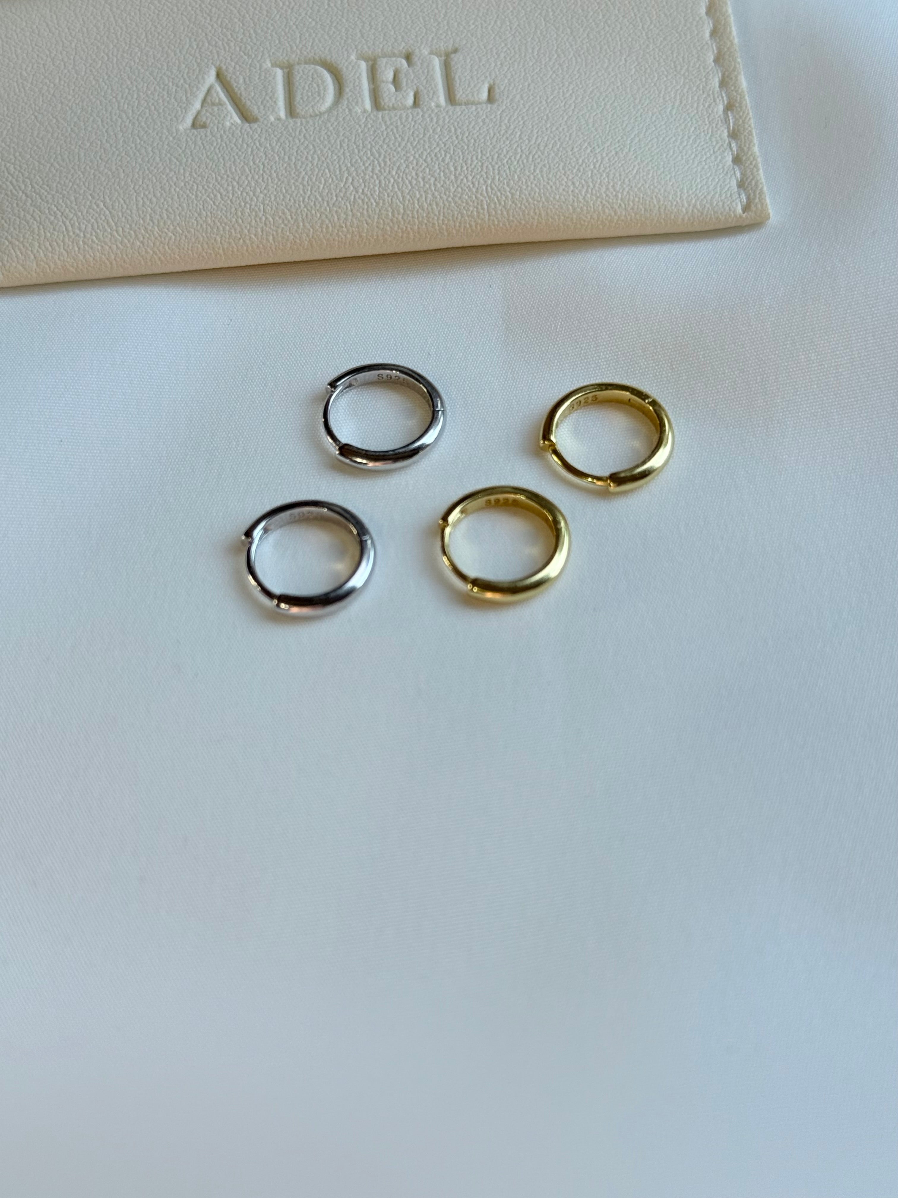 Three gold and silver hoop earrings on a white surface with 'ADEL' branding.