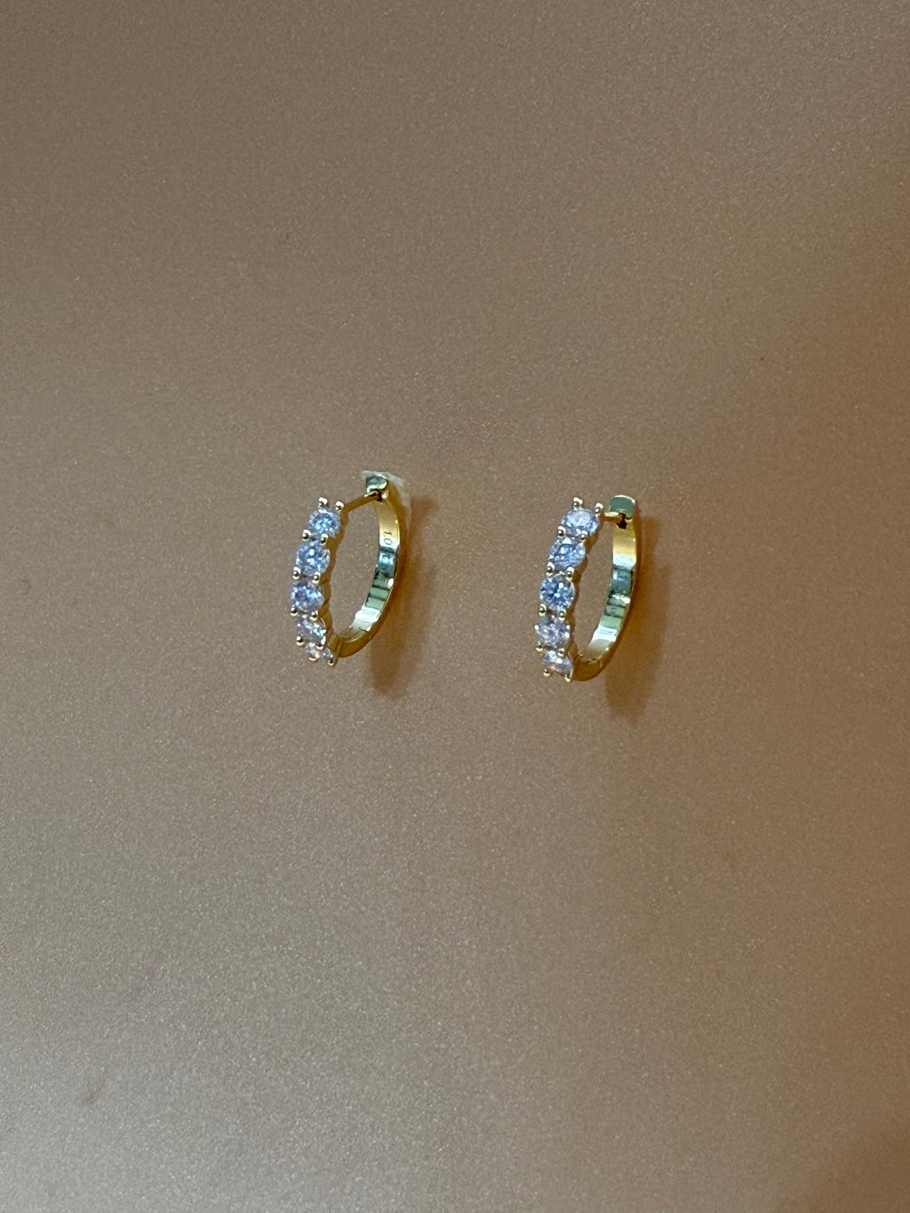 Two gold rings with gemstones on a beige background