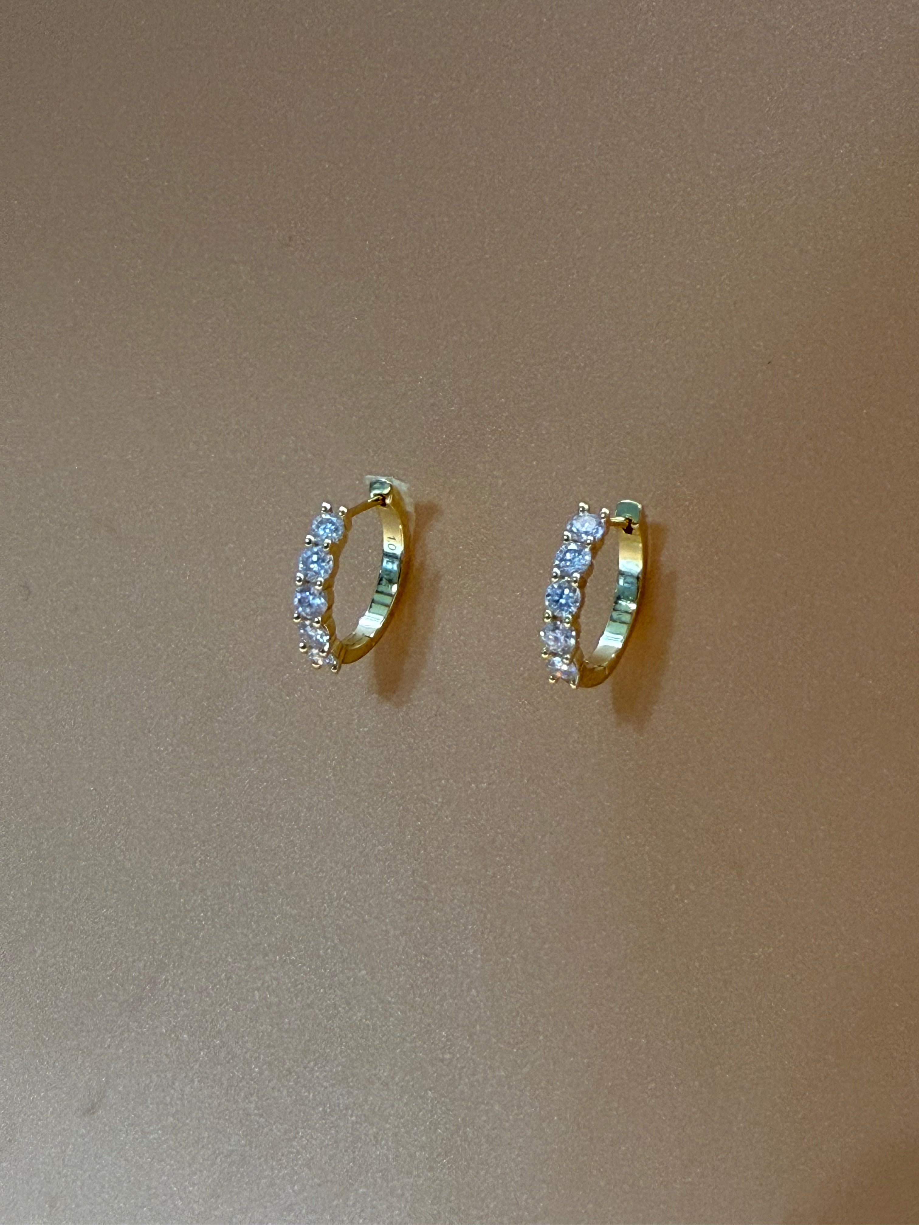 Two gold rings with gemstones on a beige background
