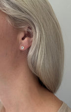 Close-up of an ear wearing a diamond earring with a plain background