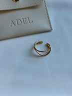 Gold ring on a light gray surface with a beige card in the background