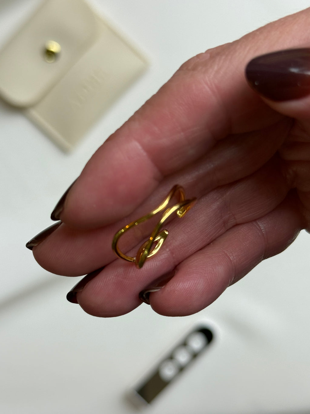 Gold hoop earrings being held between fingers with a blurred background