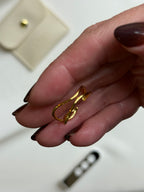 Gold hoop earrings being held between fingers with a blurred background