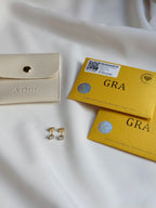 Beige wallet, gold earrings, and two yellow boxes with 'GRA' branding on a white fabric background.