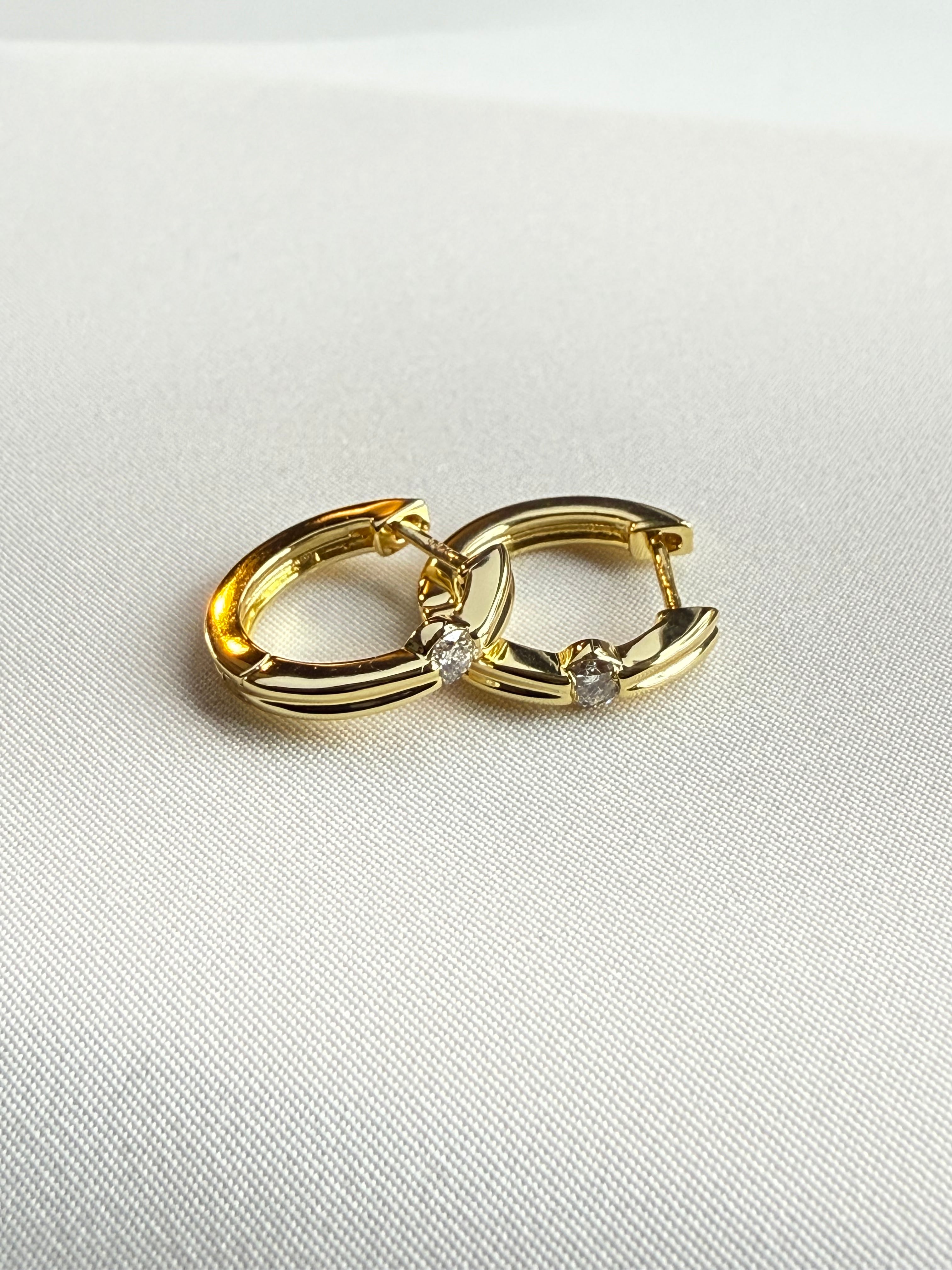 Gold hoop earring with small diamonds on a light gray background