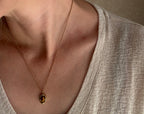 Close-up of a necklace with an oval pendant on a neutral background