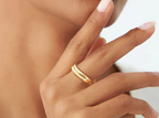 Close-up of a hand wearing a gold ring with a blurred background
